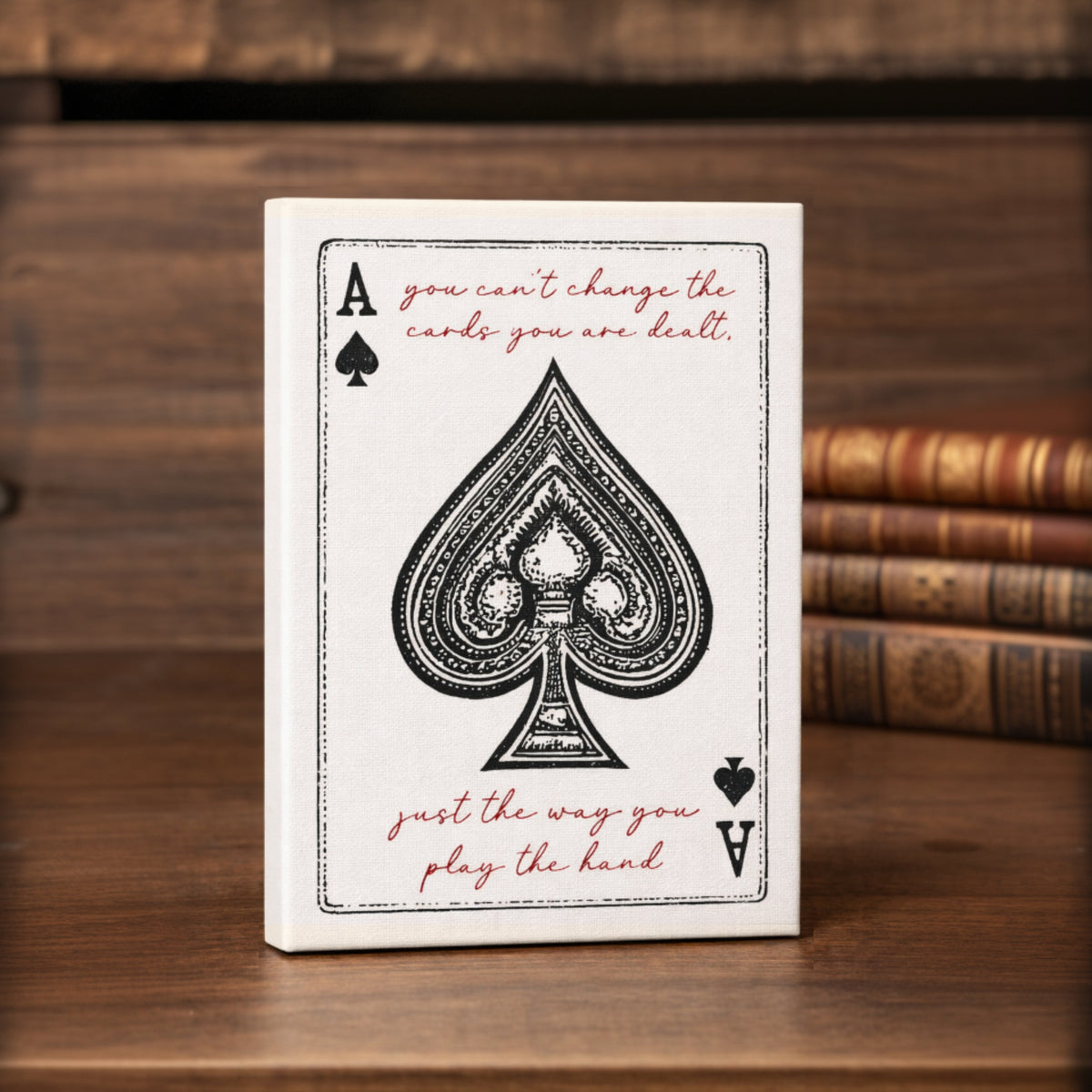 a white card with a black spade symbol and a motivational quote on it, placed on a wooden surface.