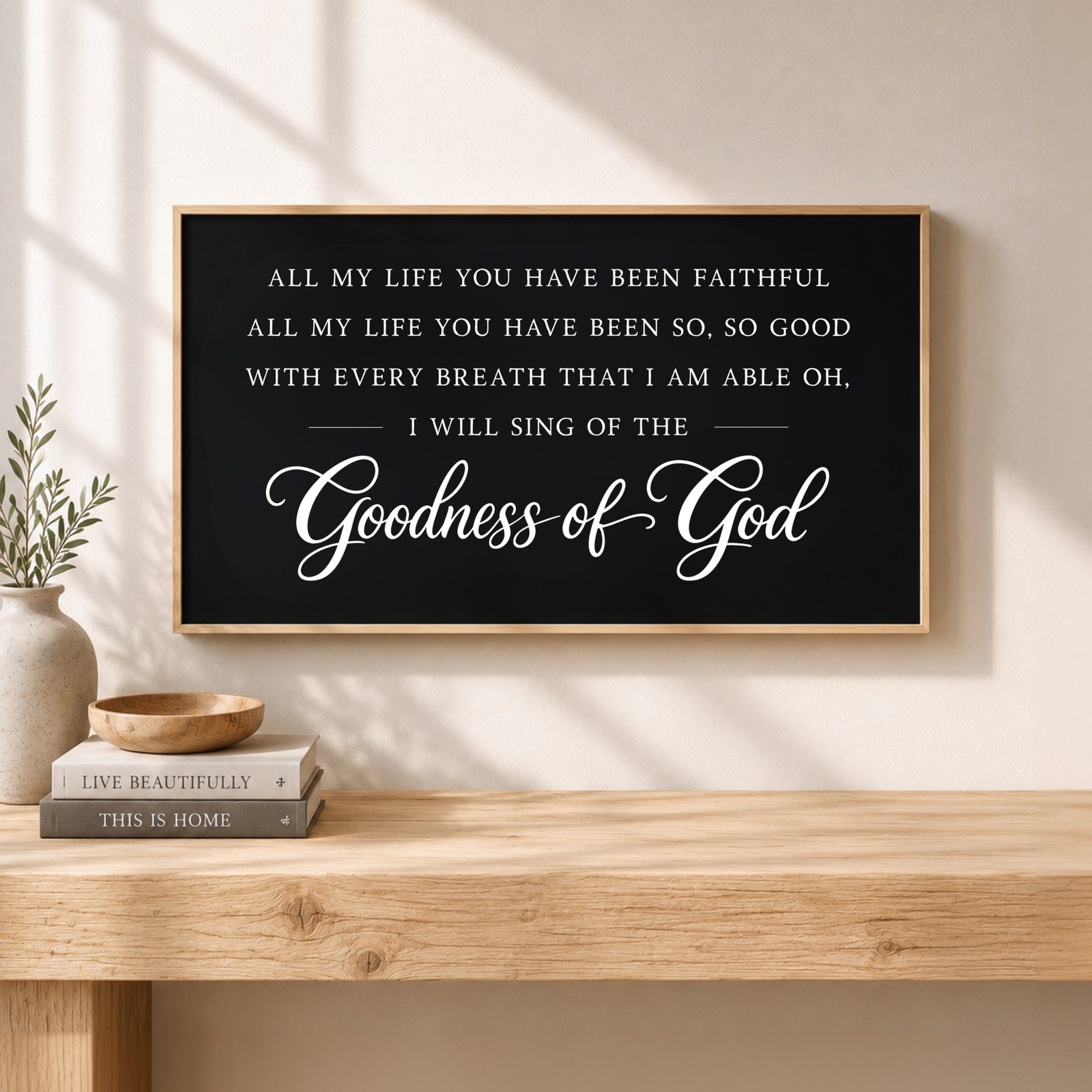 a black framed sign with white text that reads "All my life you have been faithful, all my life you have been so, so good with every breath that I am able oh, I will sing of the Goodness of God" against a wooden background.