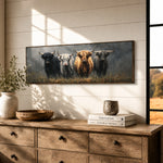 a wooden dresser with a framed painting of four yaks, two black and two brown, hanging on the wall above it. The dresser also has a small plant, a bowl, and a stack of books on top.