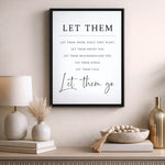 a framed quote on a wall, with a lamp, a vase with dried flowers, and a bowl of beads on a shelf below it.