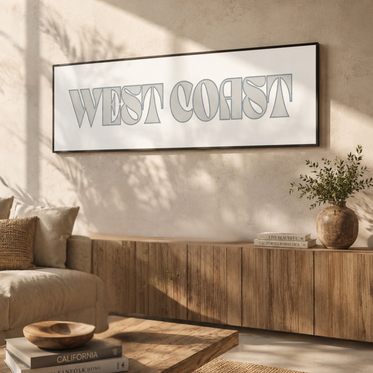 a living room with a large framed sign that says "WEST COAST" hanging on the wall. The room has a wooden coffee table, a sofa, and a bookshelf. There is also a potted plant and a vase on the coffee table.
