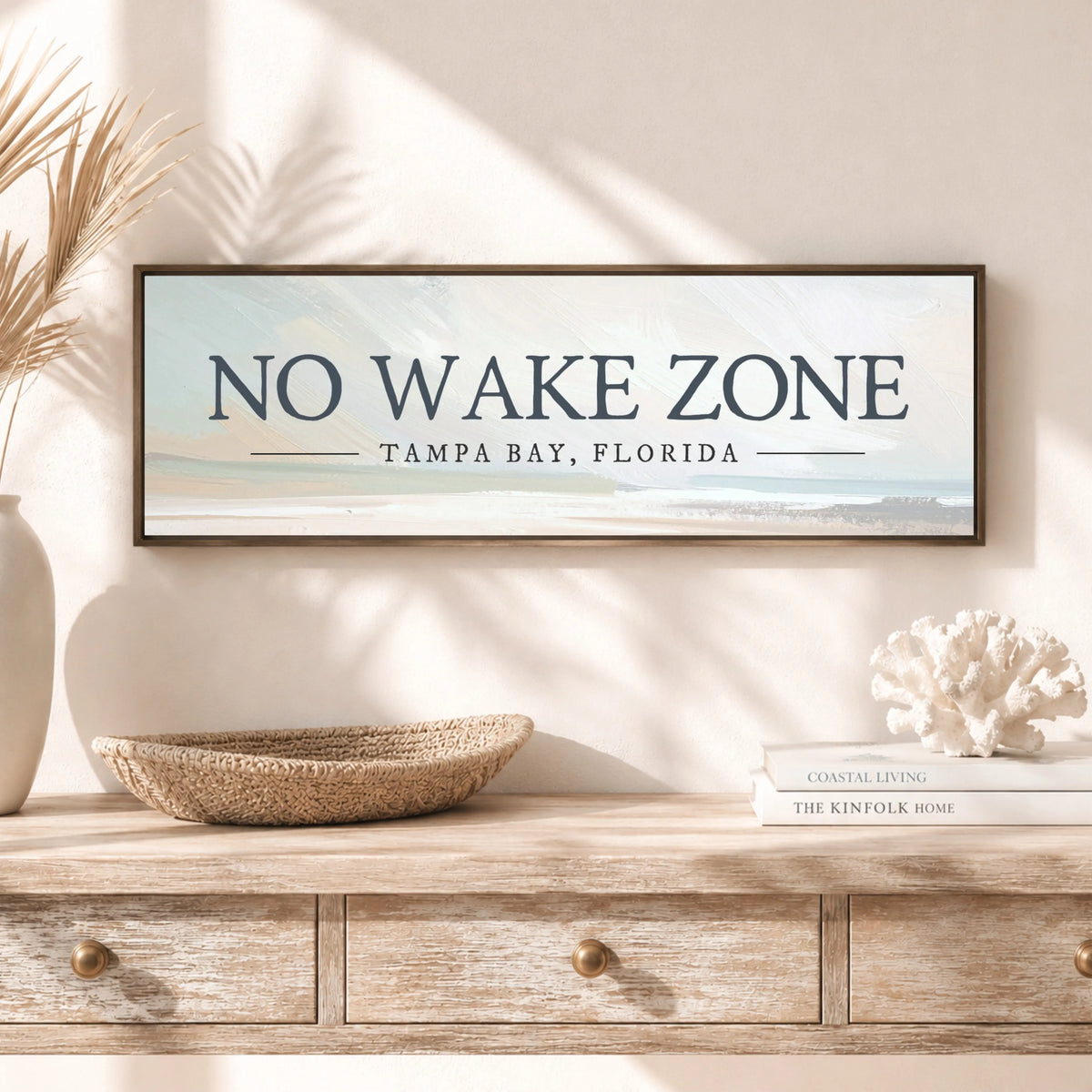 a framed sign that reads "NO WAKE ZONE" above a wooden dresser with a woven basket and a stack of books.