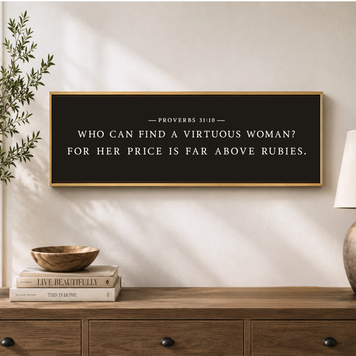 a framed quote on a wall above a wooden dresser, with a stack of books and a plant on the dresser.
