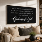 a black framed sign with white text that reads "All my life you have been faithful, all my life you have been so, so good with every breath that I am able oh, I will sing of the Goodness of God" displayed on a wall above a couch with pillows and a potted plant.