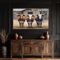 a large painting of three longhorn cattle standing in front of a barn, displayed on a dark wooden wall above a wooden cabinet or sideboard.