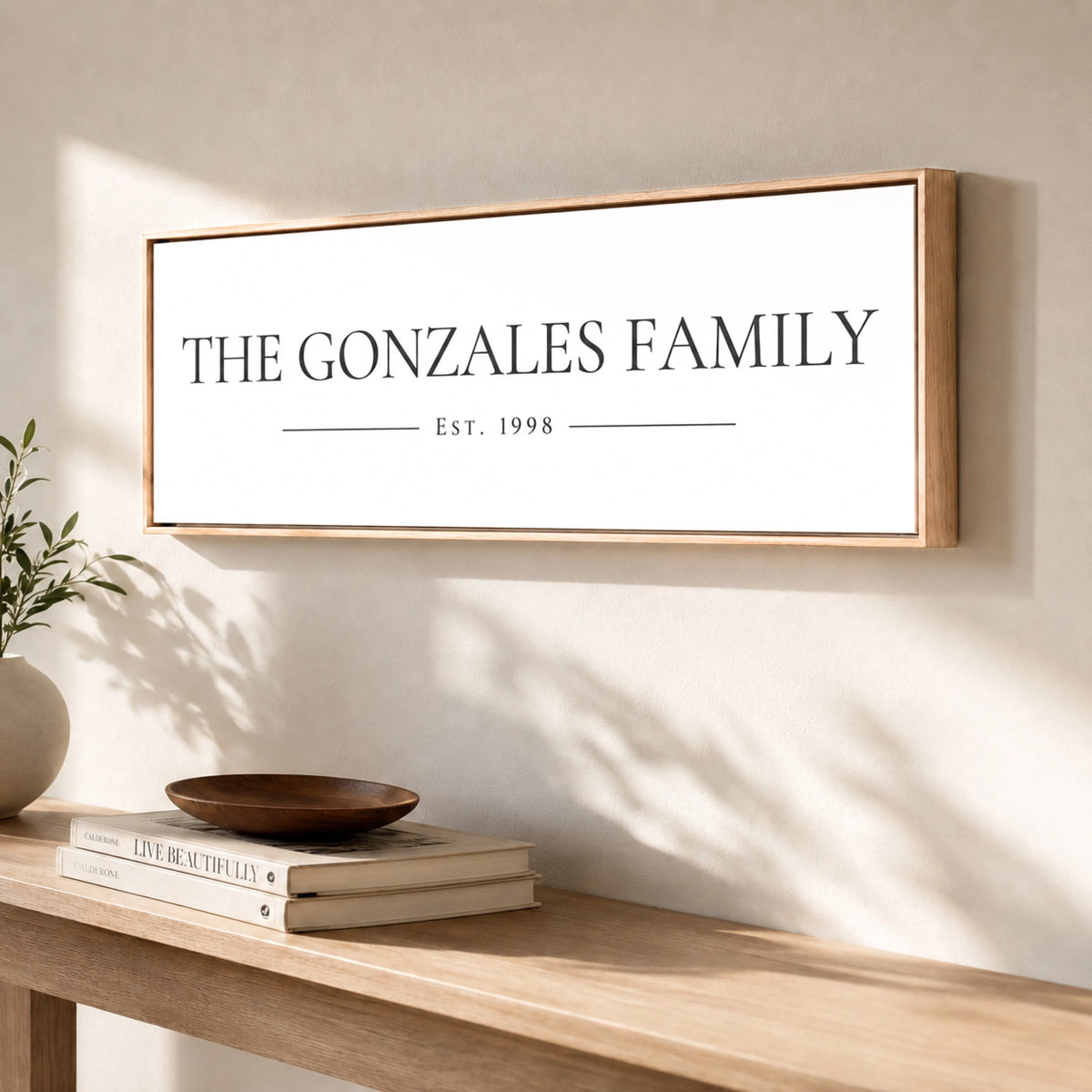 a wooden table with a framed sign that reads "The Gonzales Family" and "Est. 1998" on it. There are also some books and a decorative bowl on the table.