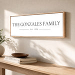 a wooden table with a framed sign that reads "The Gonzales Family" and "Est. 1998" on it. There are also some books and a decorative bowl on the table.
